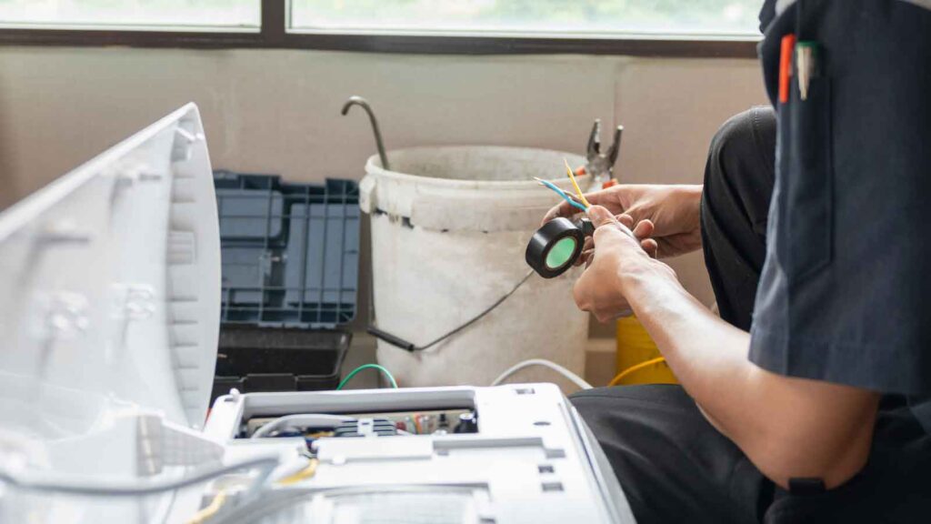 A technician working on appliance wiring with electrical tape