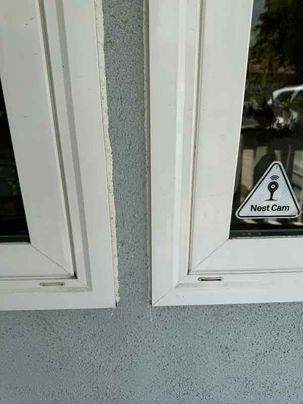 Deteriorating exterior caulk seal between white window frames, a source of water intrusion in Los Angeles